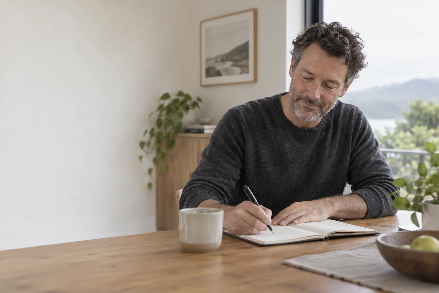 Illustrative scene of a man writing in a notebook beside a window.