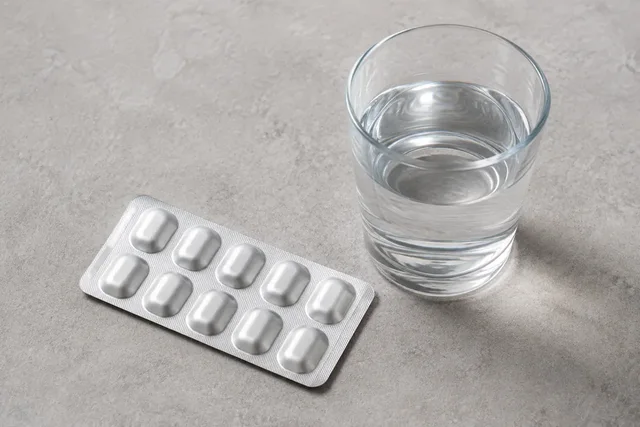 Illustrative photograph of an unlabelled medicine blister and a glass of water.