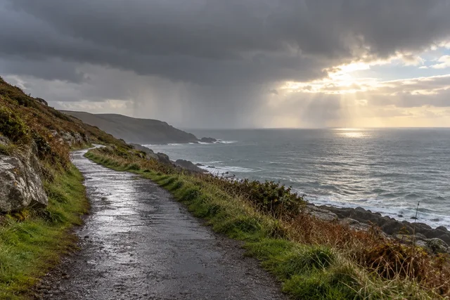 Illustrative passing rain over a quiet walking path.
