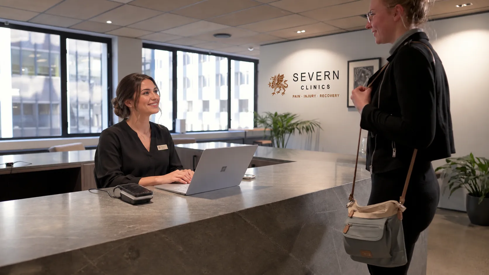 Reception at Severn Clinics, with a visitor at the desk and the clinic sign on the wall