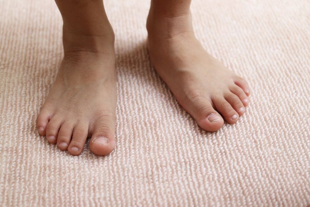 Image showing flat feet standing on carpet, a clear indicator of needing orthotics.