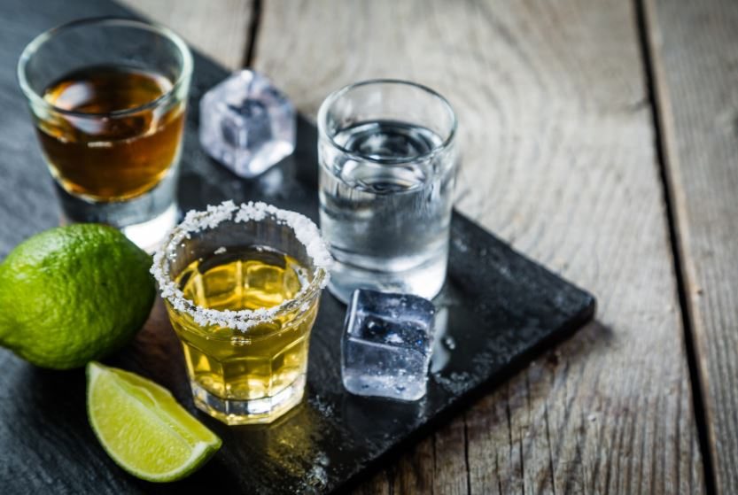 Glasses of alcoholic drinks on a wooden table.