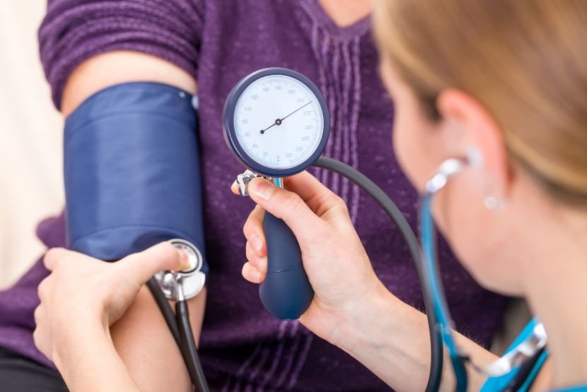 A person's blood pressure being measured with an arm cuff and gauge.