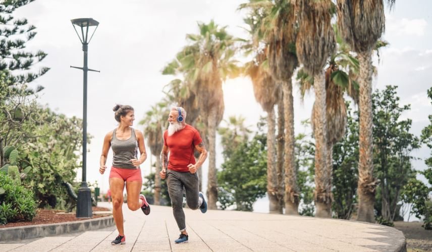 Two people running together on a path beside palm trees.