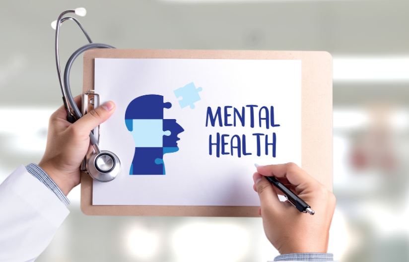 Hand writing Mental Health beside a head-shaped puzzle illustration.
