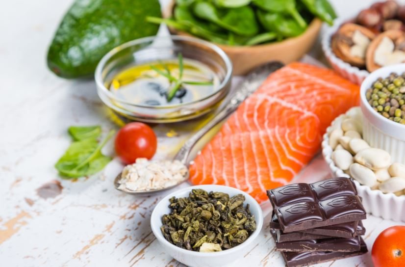 Salmon, vegetables, nuts, seeds and other foods arranged on a table.