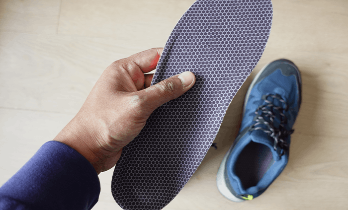 A hand holding an insole beside a shoe.
